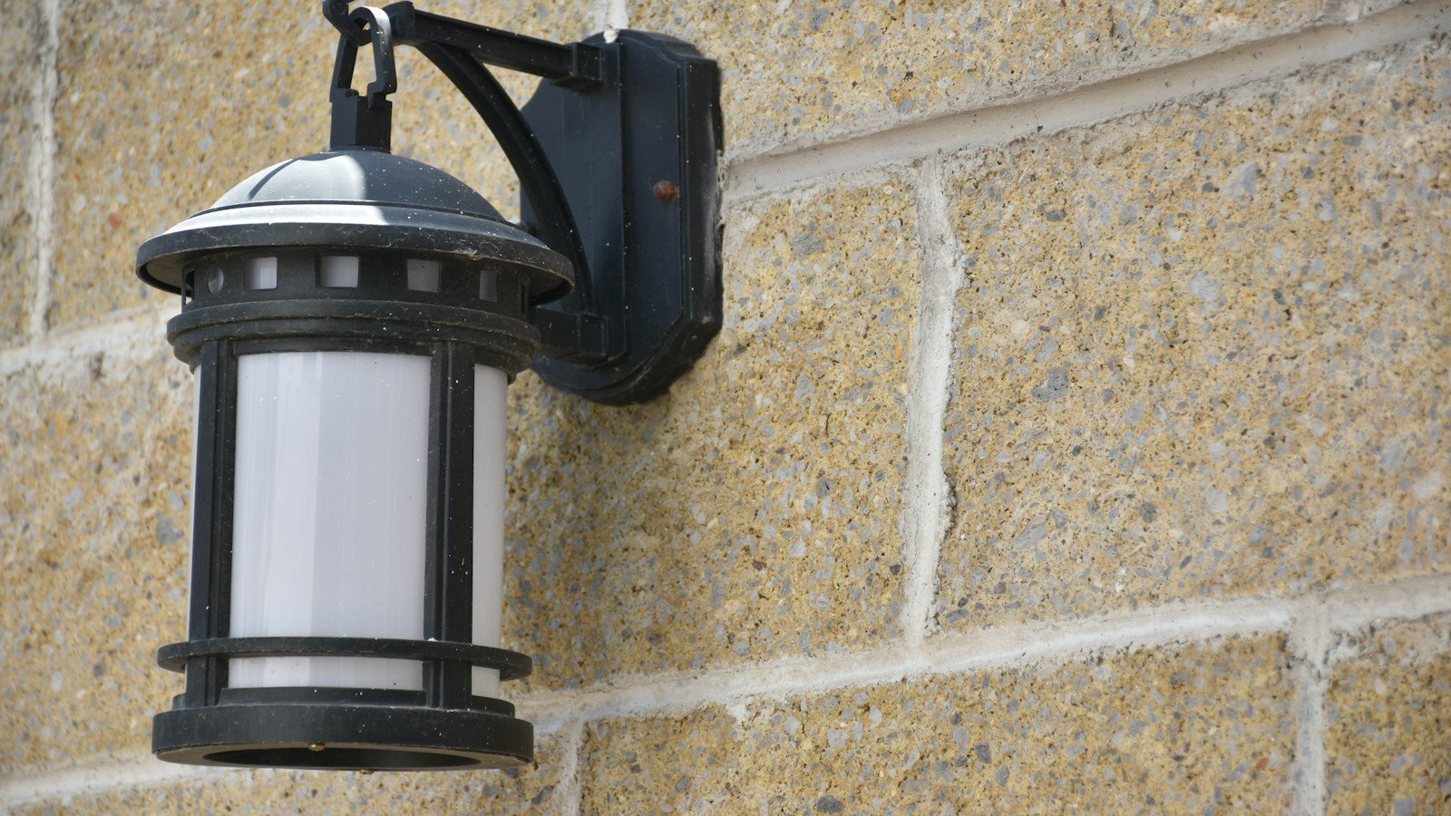 Black metal outdoor lantern mounted on a stone wall