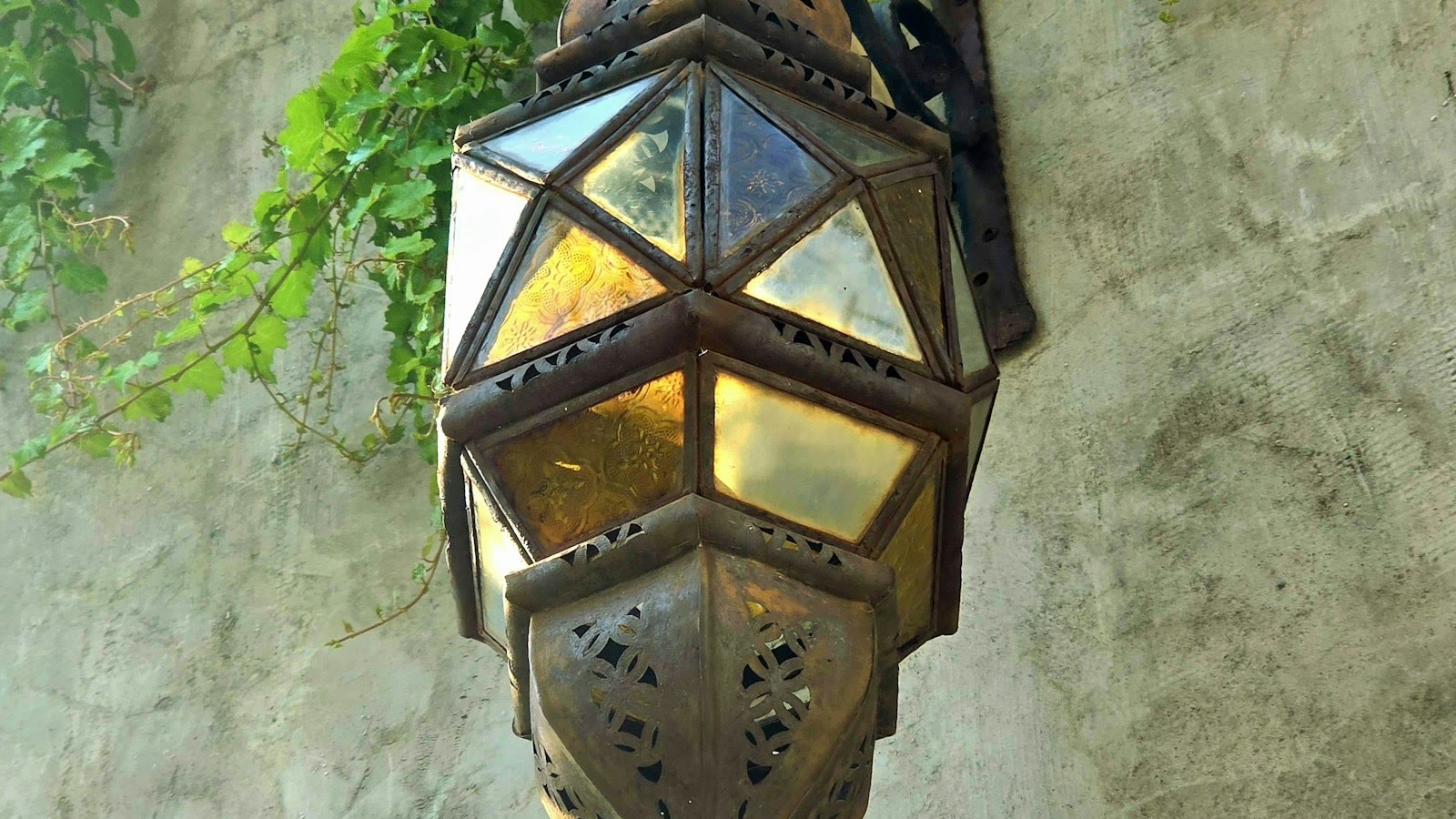 Brass wall lantern on a scroll bracket against plaster