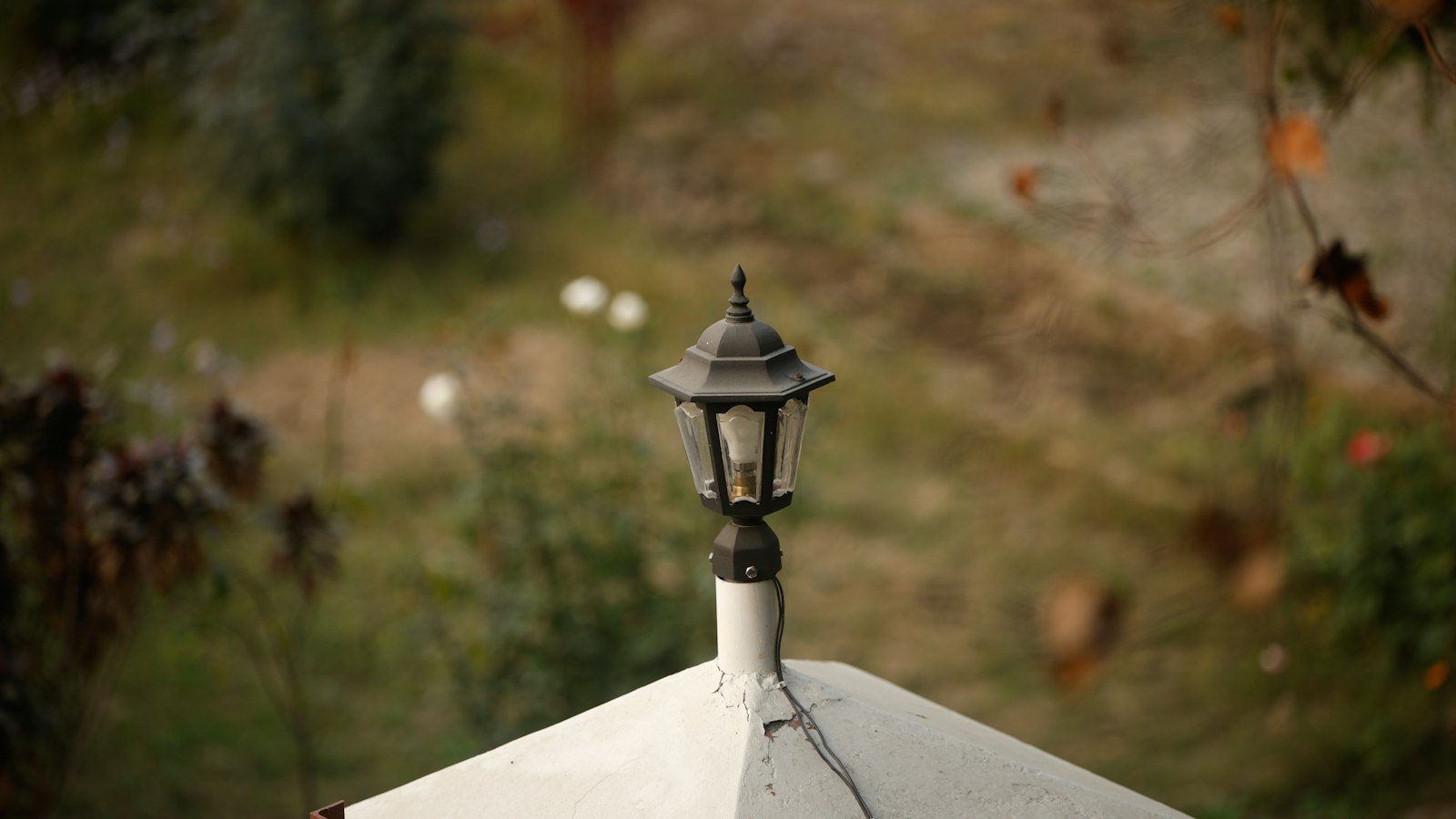 Black lantern on a peaked white gate pillar cap