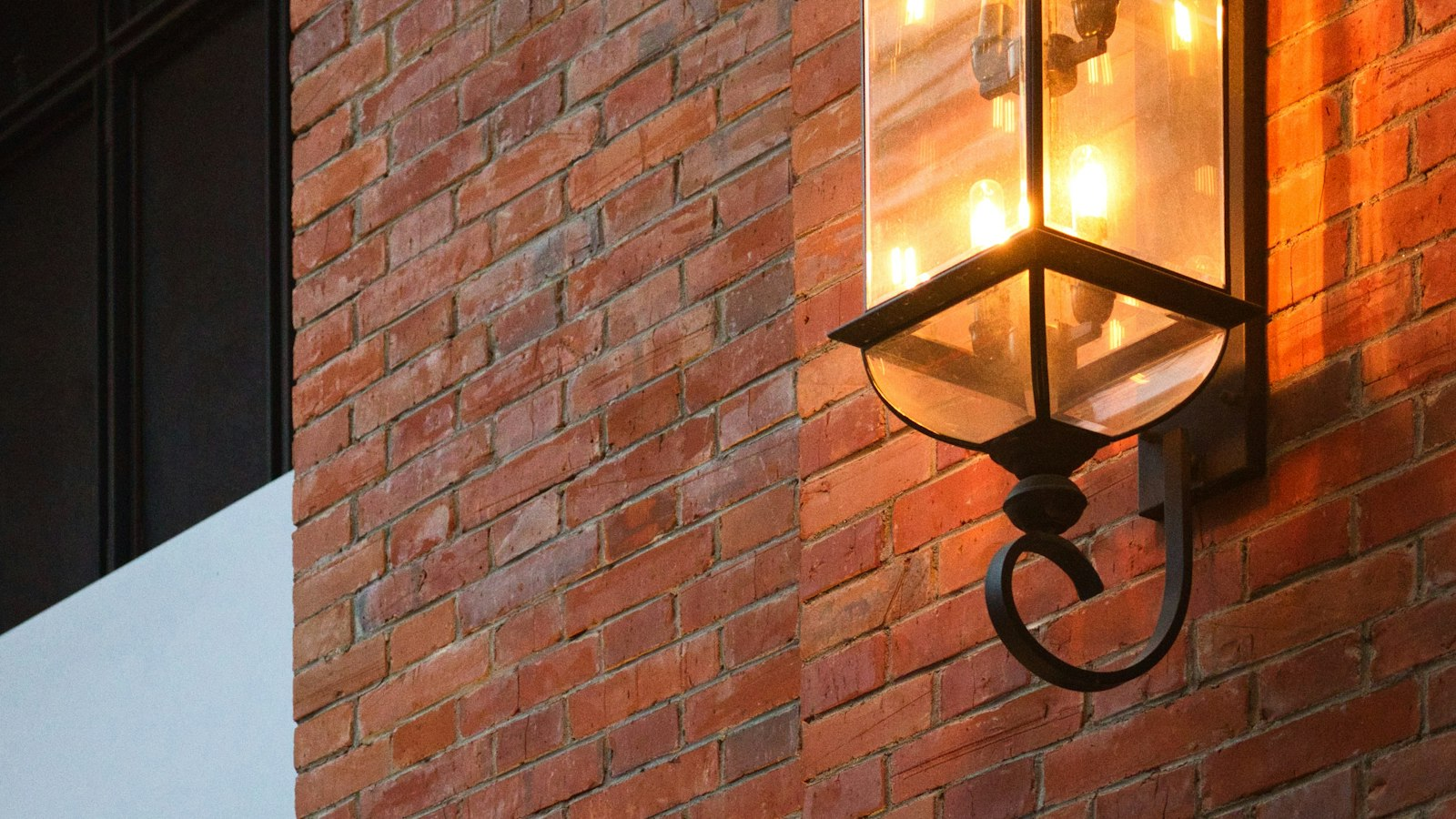 Wall-mounted lantern glowing on a brick elevation